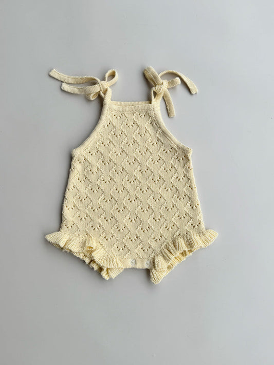 butter baby romper with lace details on a gray background