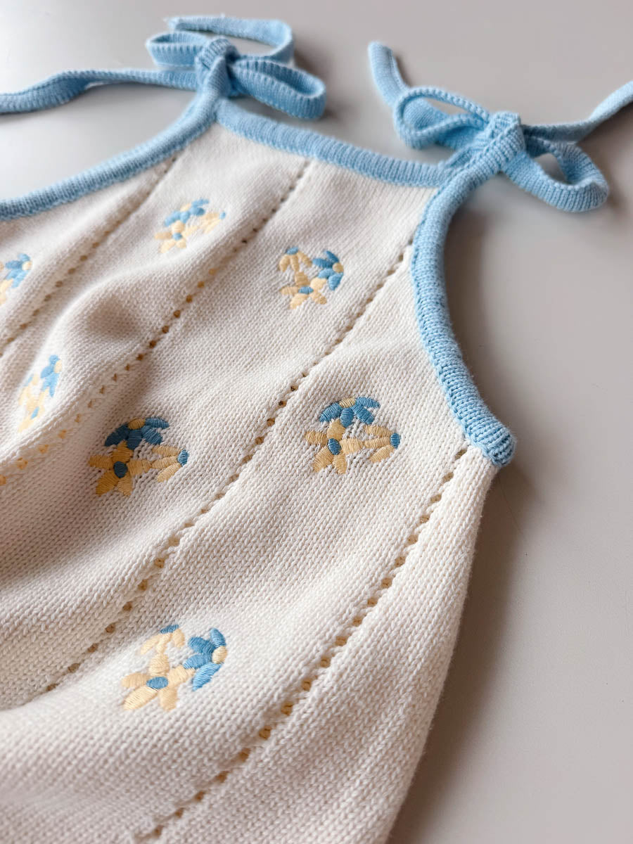 Girls dress with floral embroidery and blue straps on a light background