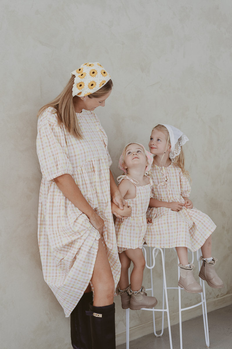 Woman and two children in matching checkered outfits against a plain background